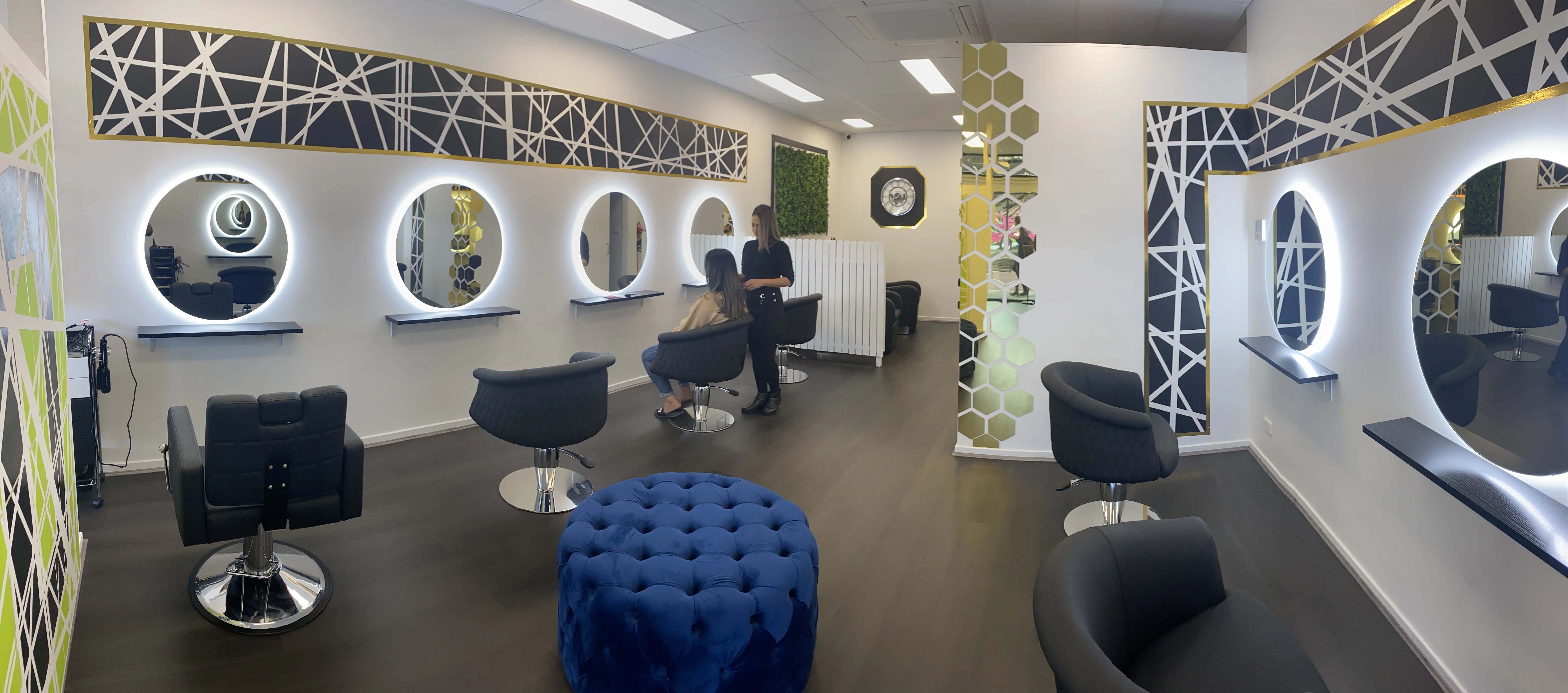 Pharaoh salon interior — ring-lit circular LED mirrors, black leather chairs, gold honeycomb pillar, green moss wall